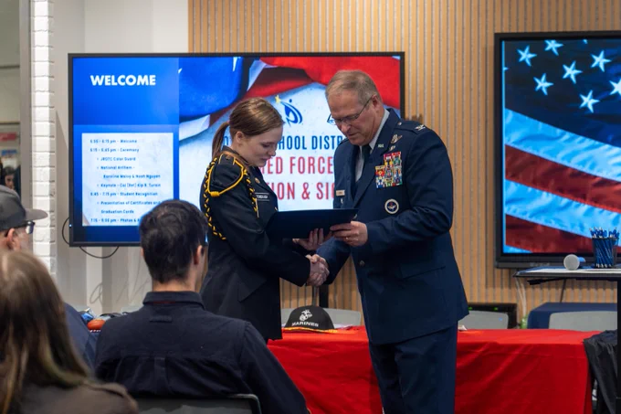 A P S D student participating in J R O T C receives a special award from the keynote speaker at the P S D Armed Forces Day Celebration & Signing event.