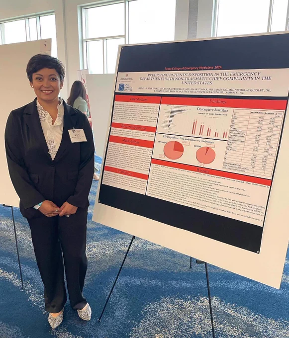 Female TTUHSC emergency medicine resident stands next to her poster.