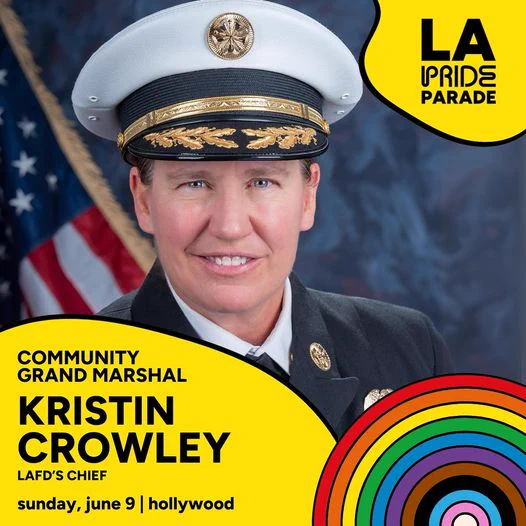 Los Angeles City Fire Department Chief Kristin Crowley smiles in her official uniform and  hat with an American Flag in the background. 

"L.A. Pride Parade, Community Grand Marshal Kristin Crowley. LAFD's Chief. Sunday, June 9. Hollywood.

LA Pride Parade. Communi
