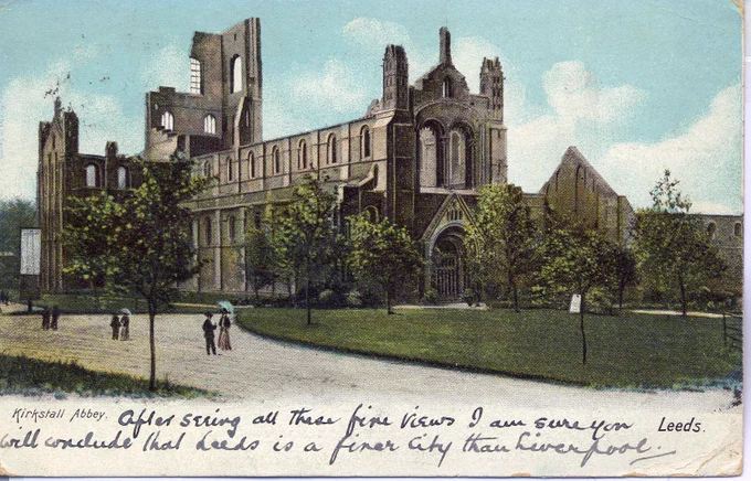 Front face of an Edwardian postcard. A painting of the ruined Kirkstall Abbey in Leeds with surrounding grass, trees, and paths, where three couples walk. in the white space below the image, the sender has written "After seeing all these fine views I am sure you will conclude that Leeds is a finer city than Liverpool."
