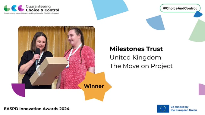 Image of two women, both with long brown hair standing on a stage. One is holding a microphone and is looking at a large brown box in their hands. The other is looking off camera and smiling. Text reads Milestones Trust, UK, The Move on Project. Winner of EASPD Innovation Award 2024.