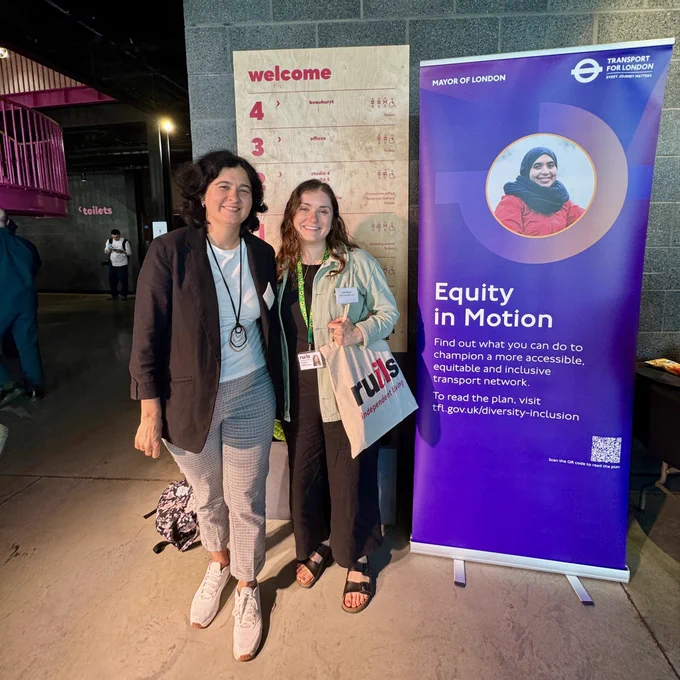 Image of Svetlana and Hallie standing next to a purple banner that reads Equity in Motion