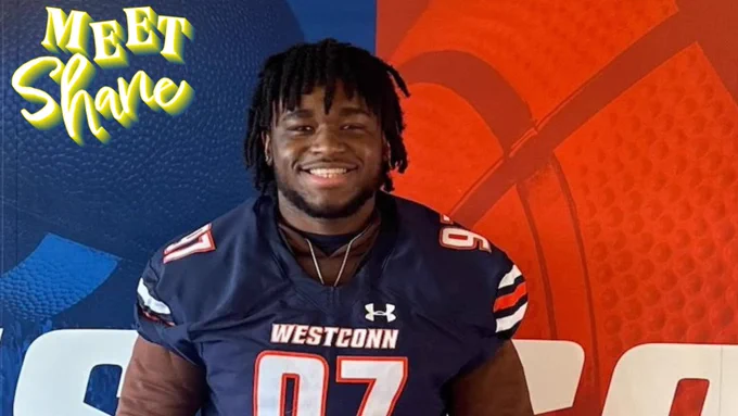 A student wearing a football uniform stands in front of a multicolored wall. 