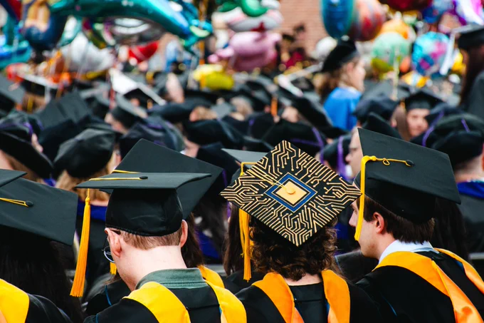 Backs of graduation caps, one cap is covered in a stunning gold circuit board design.