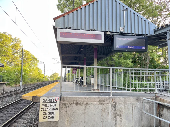 Mini-high platform at a Commuter Rail station, with digital signs displaying the next-scheduled train on Track 1. A sign also says “DANGER WILL NOT CLEAR MAN ON SIDE OF CAR”.