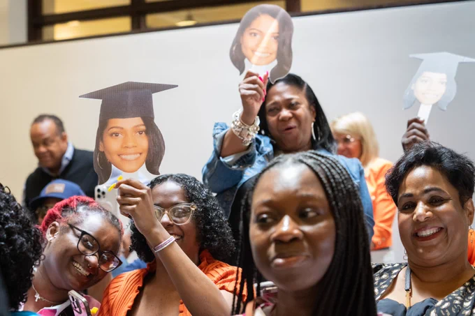 Friends and family members at the African & African American Studies diploma ceremony beam as they hold up cut-out photos of the face of their Duke 2024 graduate