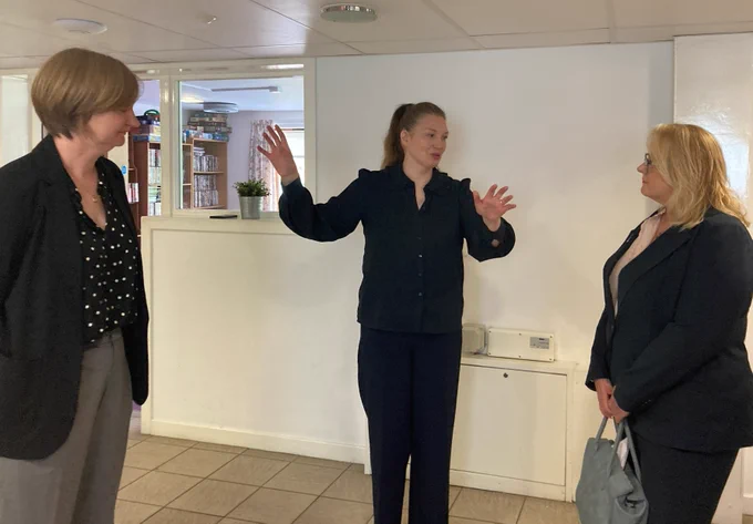 Corra CEO Carolyn Sawers (left) and Drugs and Alcohol Policy Minister Christina McKelvie hear  about the work done by Crossreach's Residential Recovery Service in Glasgow from Service Manager Catriona McCabe - all wearing dark clothing against white wall.