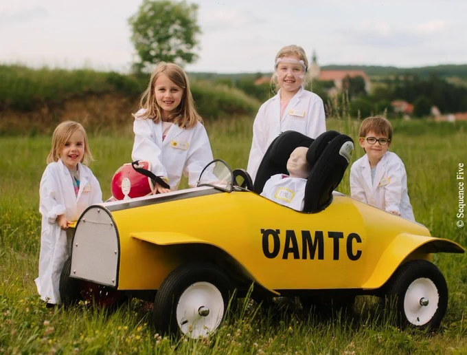 eine Gruppe von Kindern, die neben einem kleinen Spielzeugauto steht