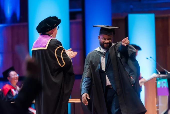 A graduate crossing the stage, pointing out to the audience
