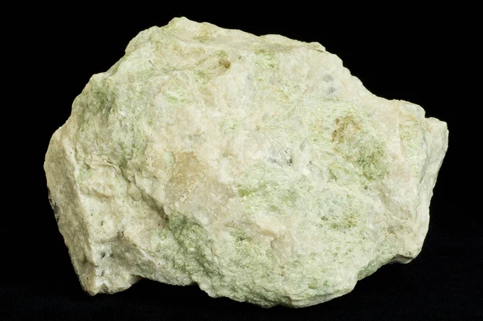 Vaalea kivenpala mustalla taustalla. Apatiitti erottuu vihertävänä pintana. Kuva: J. Väätäinen, GTK