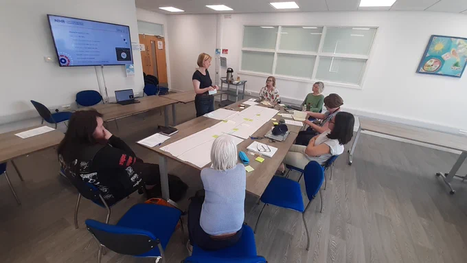 Image of a group of people sat around a conference table in discussion with the presenter