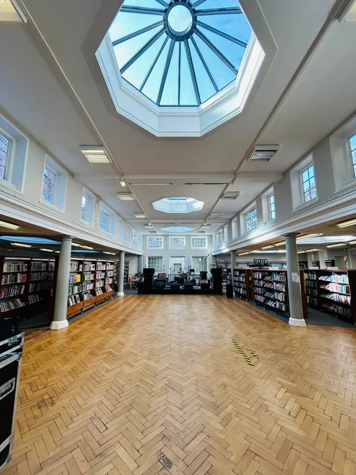 A photograph of the library with the shelves pushed back to make way for a stage.