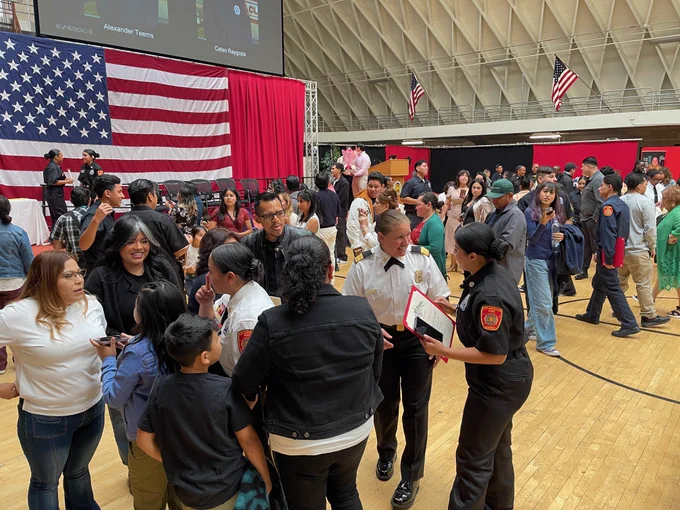 Chief Crowley speaking with students while many family members are in the area congratulating other students