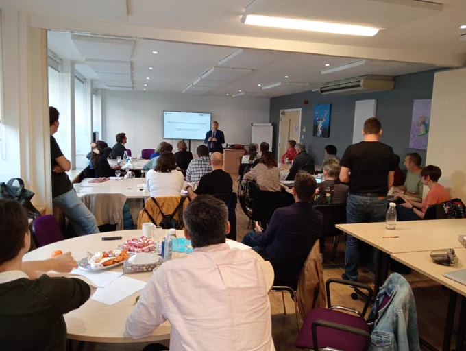 En la imatge es pot veure la sala on s'ha dut a terme la reunió. D'esquenes, tots els assistents escoltant la intervenció d'un professional. Els assistents estan distribuïts en taules de treball.