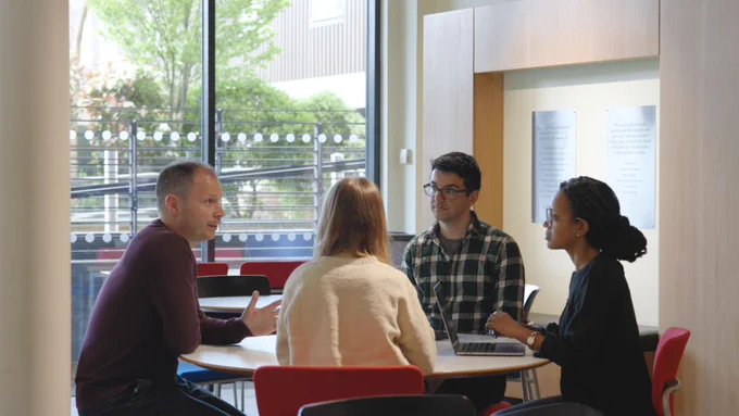 a PhD supervisor sits talking to students at Cicely Saunders Institute at King's