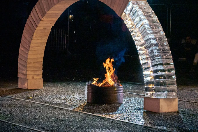ARCH is a performance that happens outdoors and shows 2 people building a freestanding arch made with concrete and ice, with sounds of a choir singing from where the audience sits. At the end the arch might fall down or stay up. 