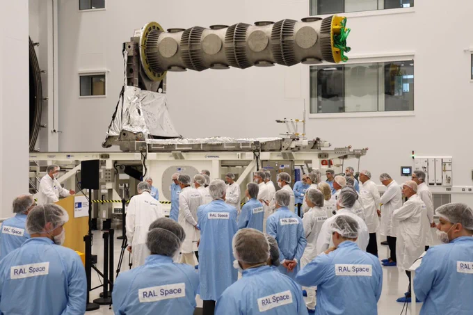 Guests wearing clean room gowns, standing inside the National Satellite Test Facility's large space test chamber