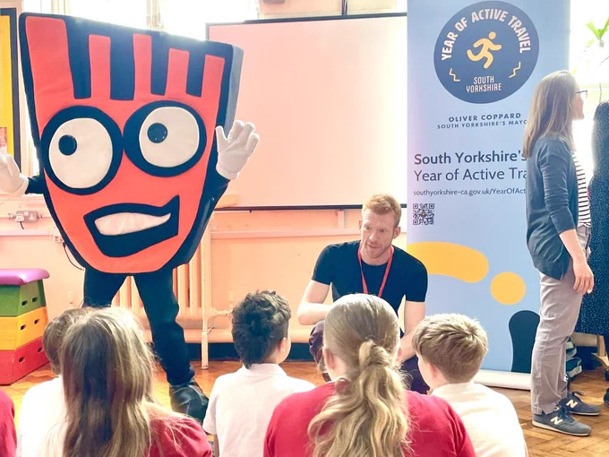 Ed Clancy and a man dressed in a giant orange foot costume to talk primary school children