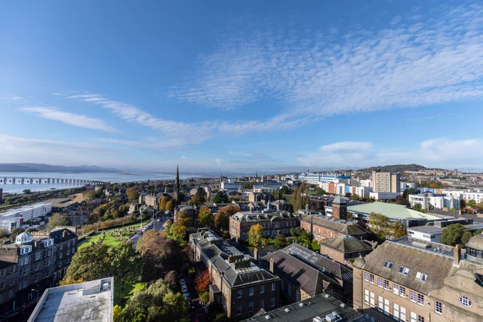 Cityscape image of Dundee with buildings in the foreground and the River Tay in the distance.