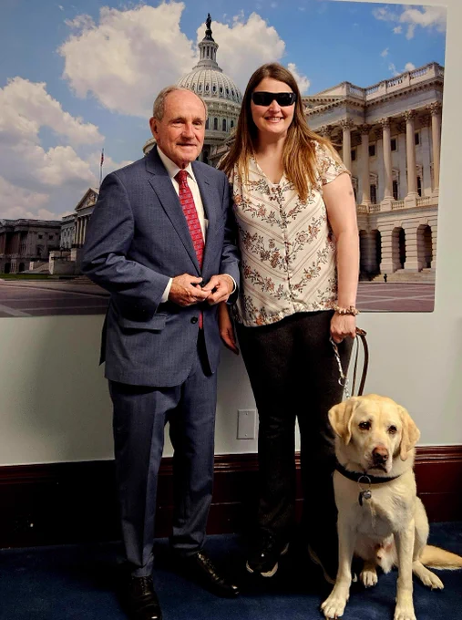 Marybeth standing with her guide dog and Senator Risch.