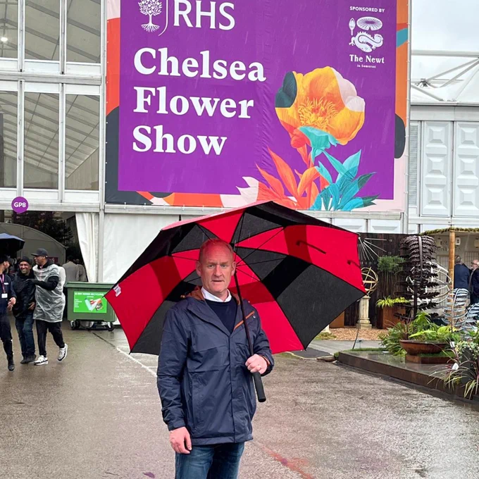 Gareth Boyd at the Chelsea Flower Show, stood under an umbrella