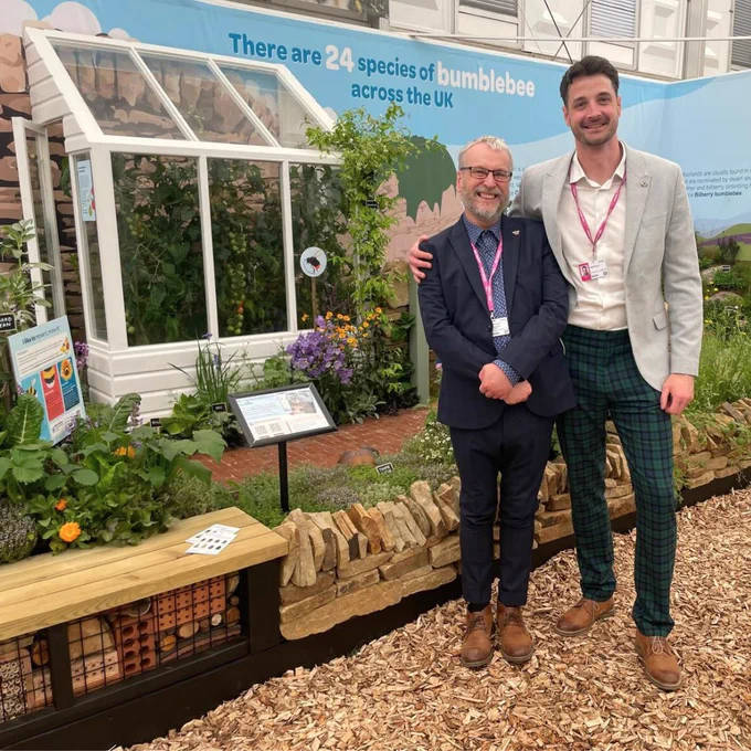 Two members of Trust staff standing and smiling in front of the Diversity is Queen exhibit.