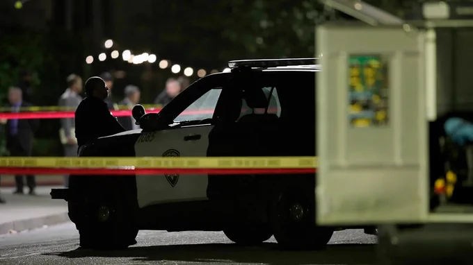 Police vehicle at night with no lights on, inside a taped-off area
