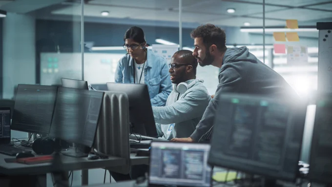 Workers in an office review data on computer screen