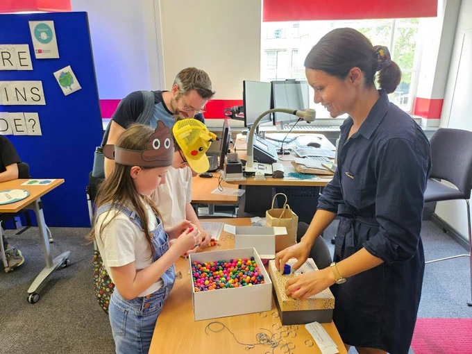 Two children string coloured wooden beads together to make keychains.