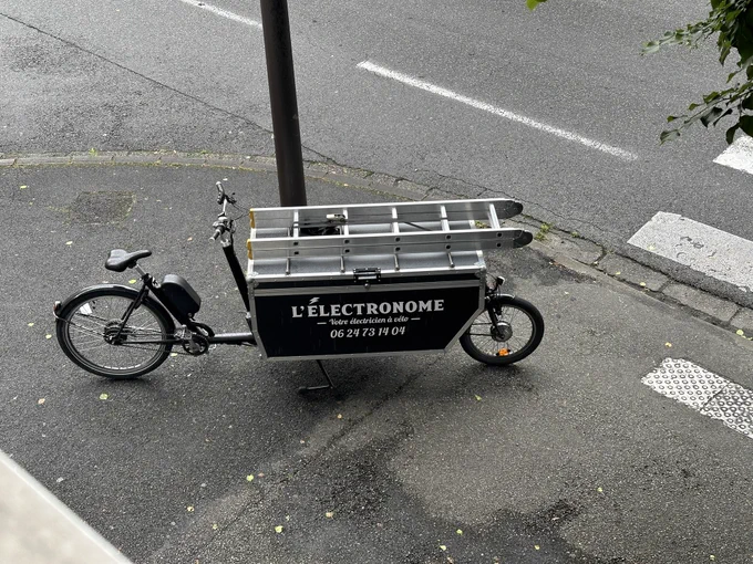 A bucket cargo ebike set up for an electrician with ladder mounted on top. Writing on bucket says “L’Electronome” your bike-based electrician.