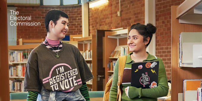 Two students in a library, one wearing a tshirt that says 'I'm registered to vote'