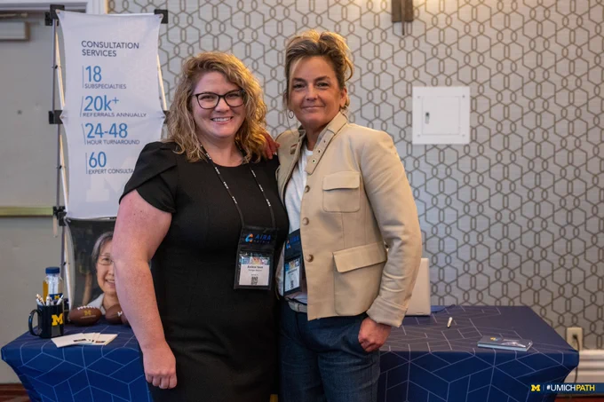 Andrea Hawk and Jackie Goodman pose for a photo at the MLabs exhibitor booth during the 2024 Pathology Informatics Summit. 