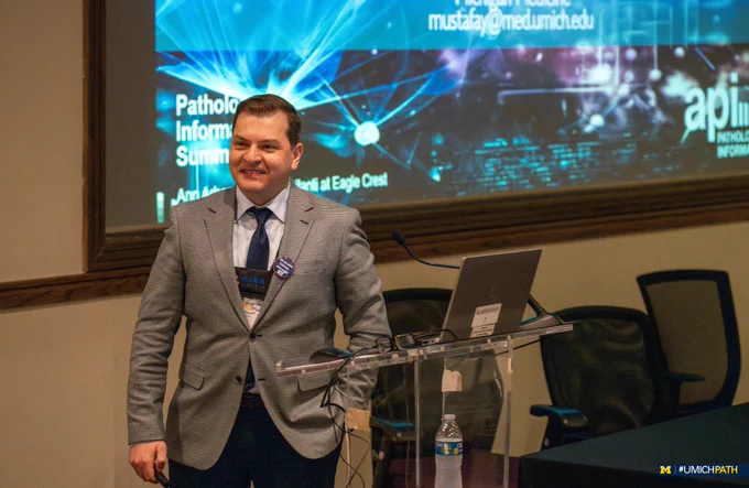 Dr. Mustafa Yousif smiles while being introduced prior to his presentation at the 2024 Pathology Informatics Summit. 
