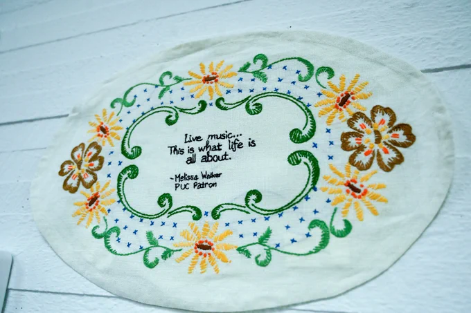 An embroidered oval with flowers, on the inside it reads "Live music ... this is what life is all about." Attributed to Melissa Walker, a Princeton University Concerts patron