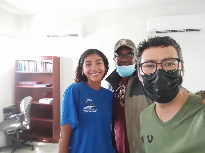 A selfie of Manuel and two others standing in an indoor office.