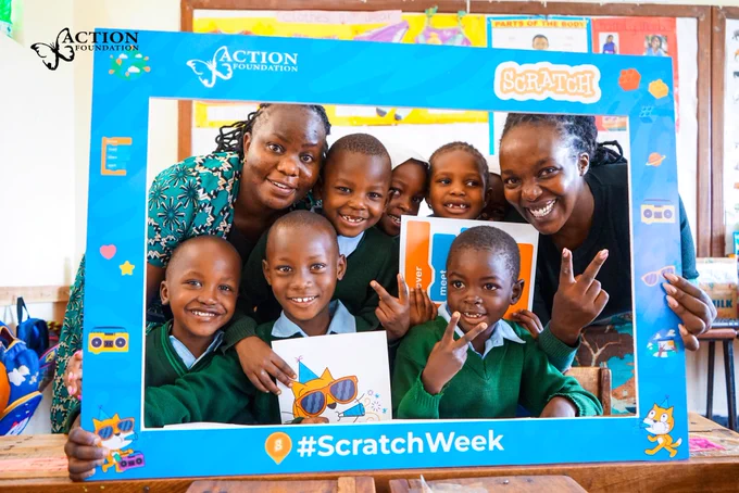 A group photo of the learners holding a photo frame with Stacy Irara and their teacher