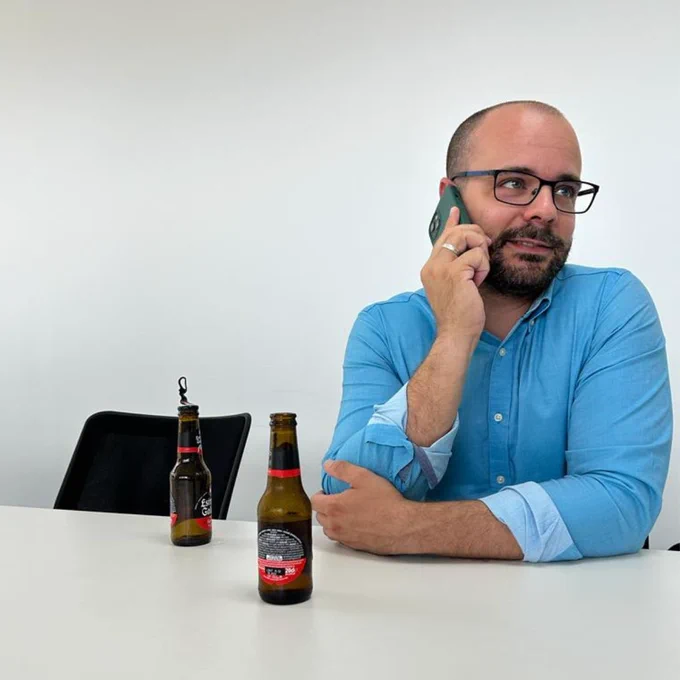 Álvaro Quirós hablando por teléfono, relajado, con una cerveza encima de la mesa