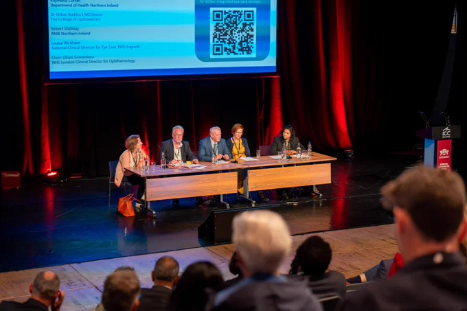 The panel discussion takes place on a stage at the Royal College of Ophthalmology Conference with five people seated behind a table, each with a microphone.

In the foreground, the backs of audience members' heads. Panel, left to right:
Louisa Wickham, NHS England, National Clinical Director for Eye Care, Robert Shilliday, Director, RNIB Northern Ireland, Raymond Curran, Head of Ophthalmic Services, Strategic Planning & Performance Group, Department of Health NI
Dr Gillian Rudduck MCOptom, President, The College of Optometrists, Chair: Dilani Siriwardena, NHS London, Clinical Director for Ophthalmology