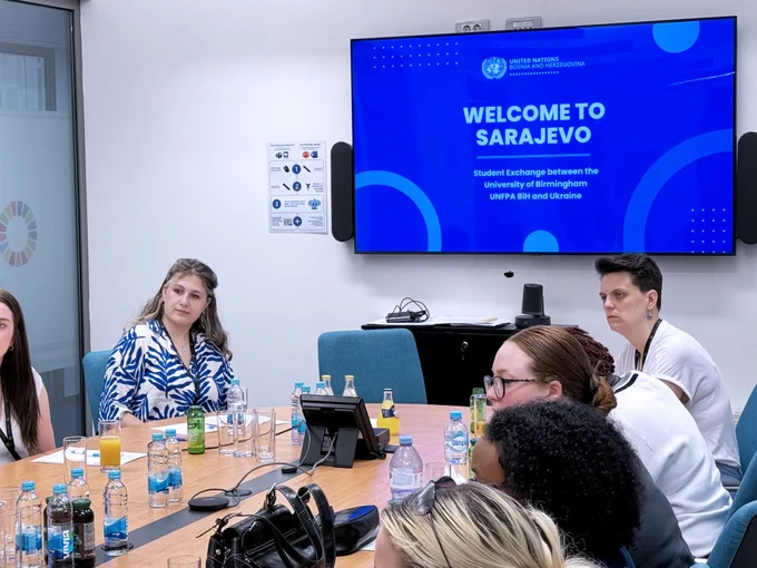 Students listening to the meeting while a presentation is shown on the tv behind them. 