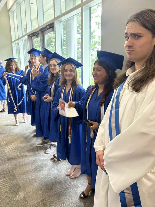 About seven graduates smiling for a photo while getting ready.