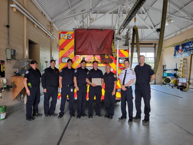 Photo of CTO Mathieu in front of a fire truck with Delta platoon to acknowledge his 20 years of service with Waterloo Fire Rescue