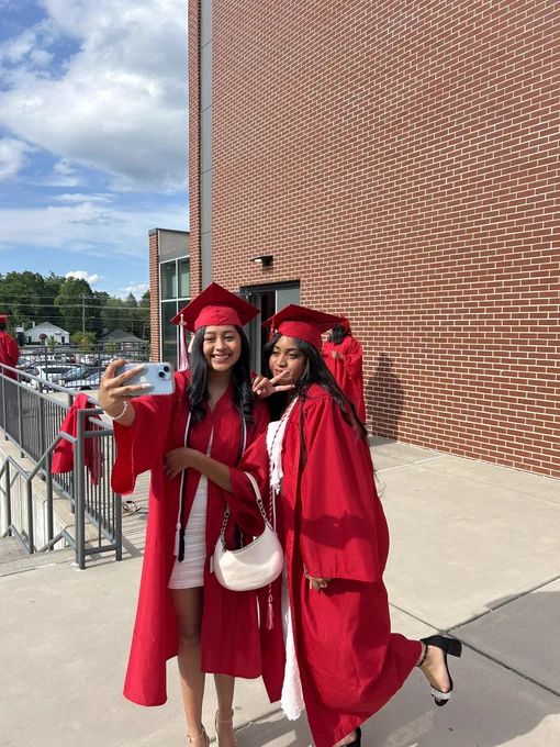 Two graduates taking a selfie in their caps and gowns.