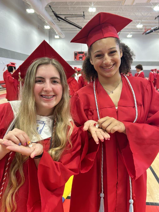 Two graduates holding small toy ducks.