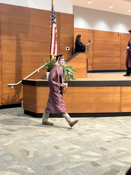 A graduate walking with his diploma.