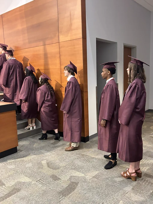 About 10 graduates in line waiting to cross the stage.