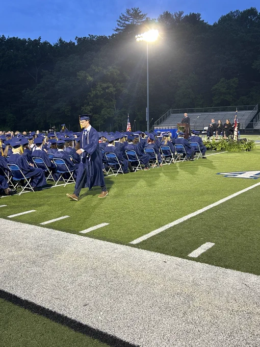 A graduate walking across the football field.