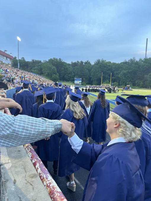 A graduate shaking a fans hand.