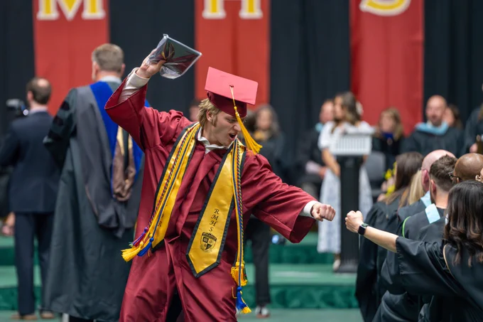 A student fist bumps a teacher after receiving his diploma.