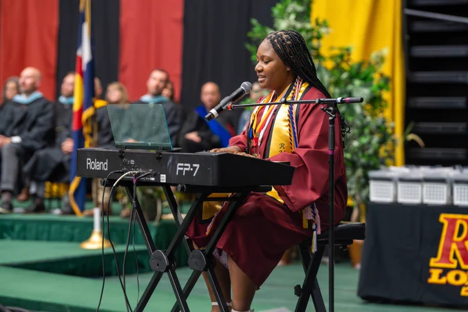 A student performs an original song in front of the class of 2024 at graduation.