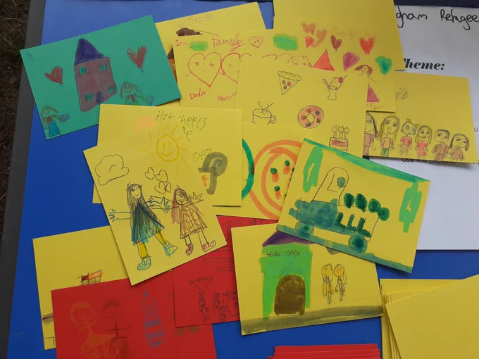 Photo of children's drawings on yellow, green or red card.